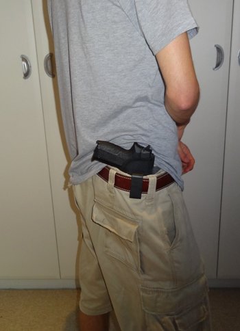 Handgun on belt exposed from under T-shirt